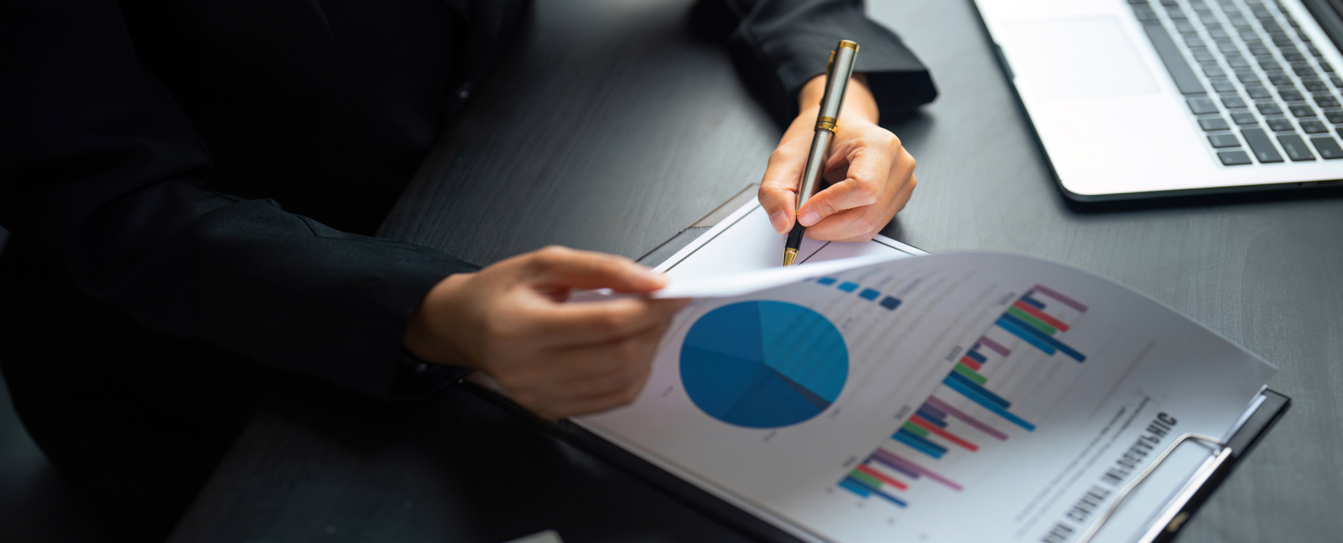 3. https://uat.ols.com.sg/wp-content/uploads/2025/02/banner-home2.jpg Close-up of a businessperson analyzing financial charts and graphs on a report